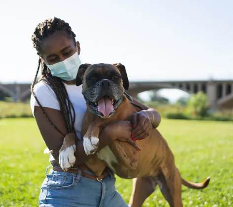 Girl wearing a mask and holding a dog
